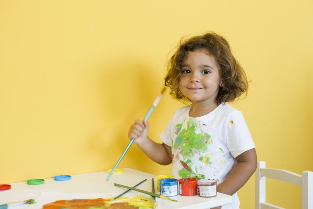 preschool kid holding a paintbrush and painting