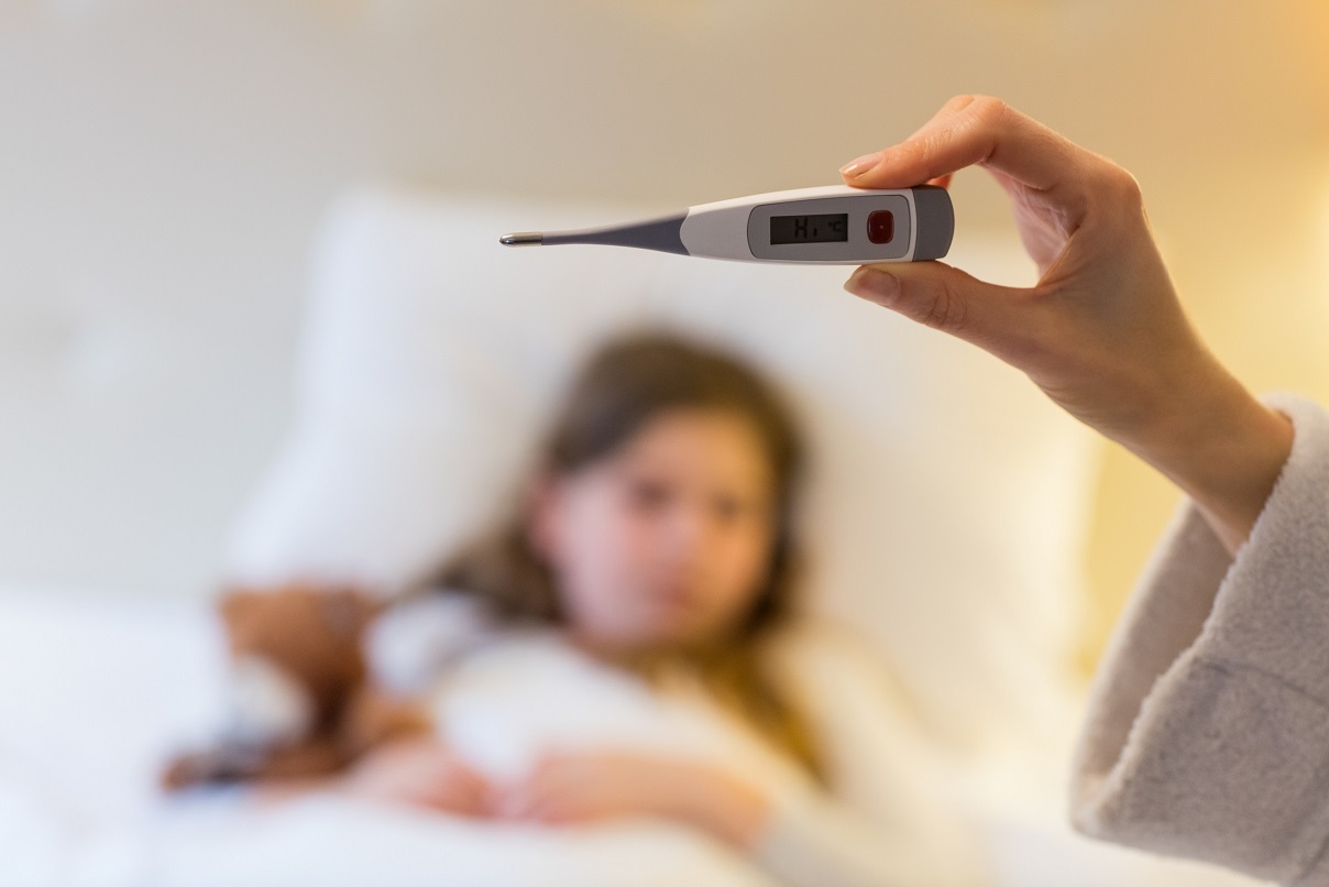 Mother checking body temperature on thermometer in bedroom