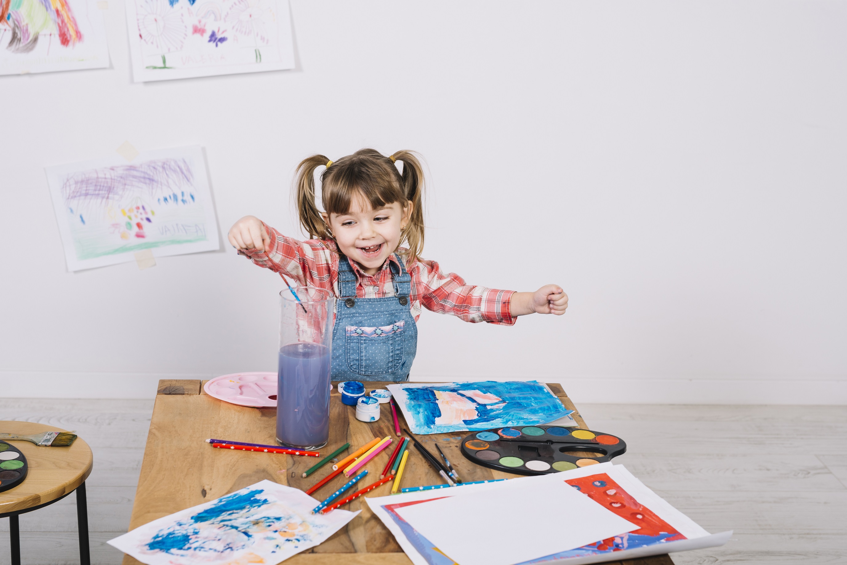 Girl happily painting using paintbrush and watercolour