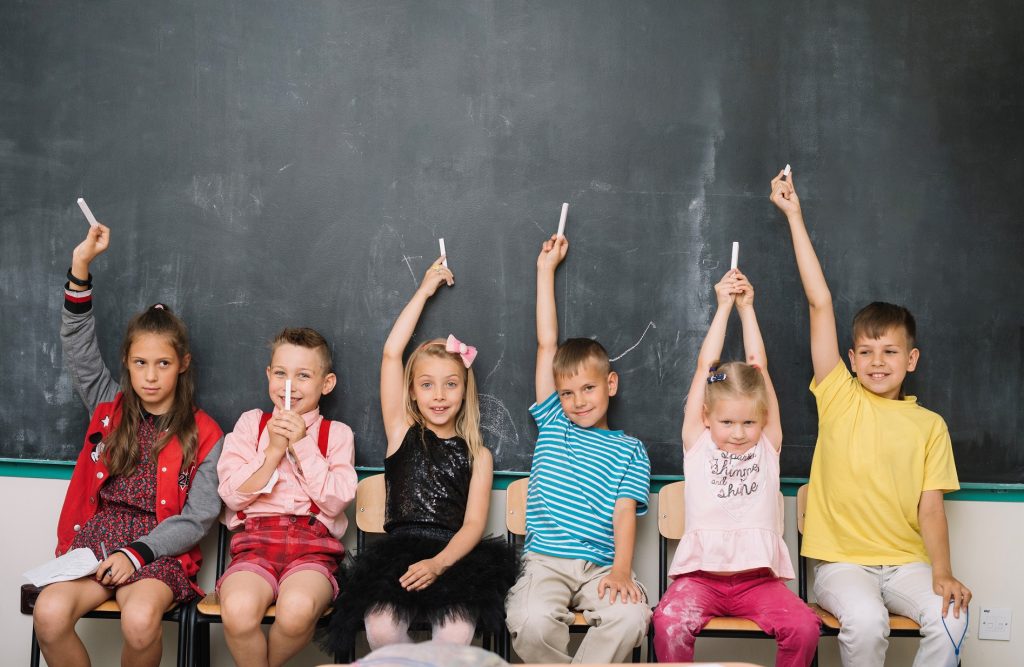 children holding chalks up in class