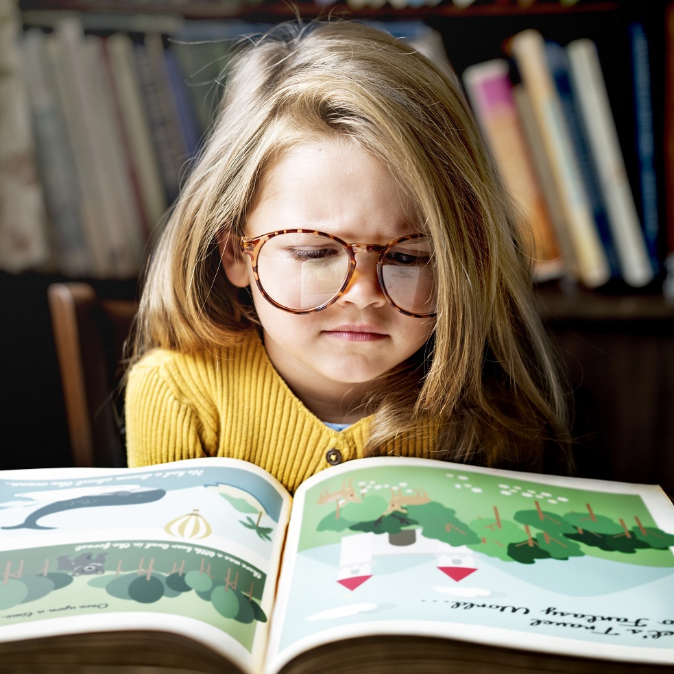 Cute and adorable little girl with glasses getting stressed out as she is reading