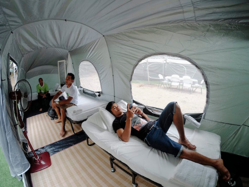 Men resting on single beds in a tent