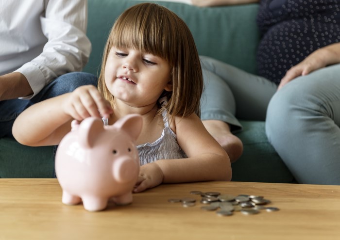 girl putting coins in her piggy bank