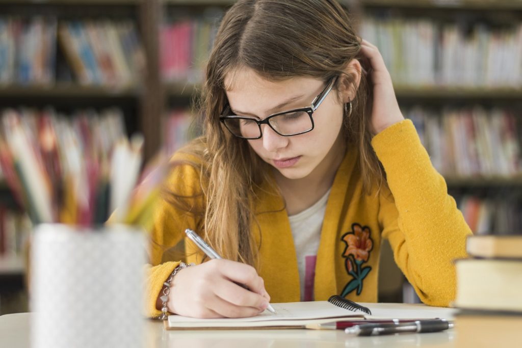 girl with glasses studying in the library