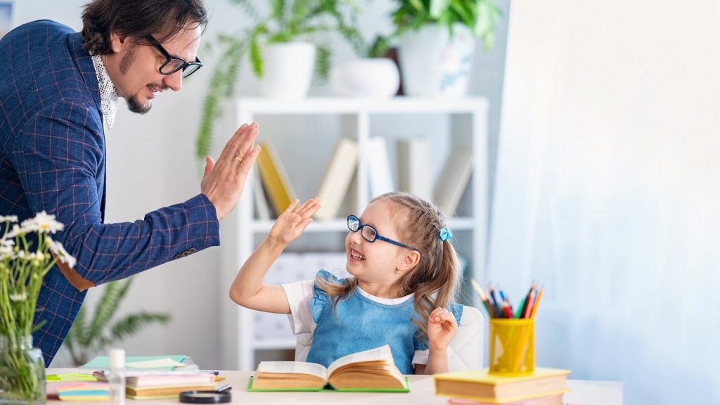 cute little girl is happy to do lessons with a teacher at home. Primary school teacher. Preschool education. Dad helps with homework. Individual training. Teamwork. High five.