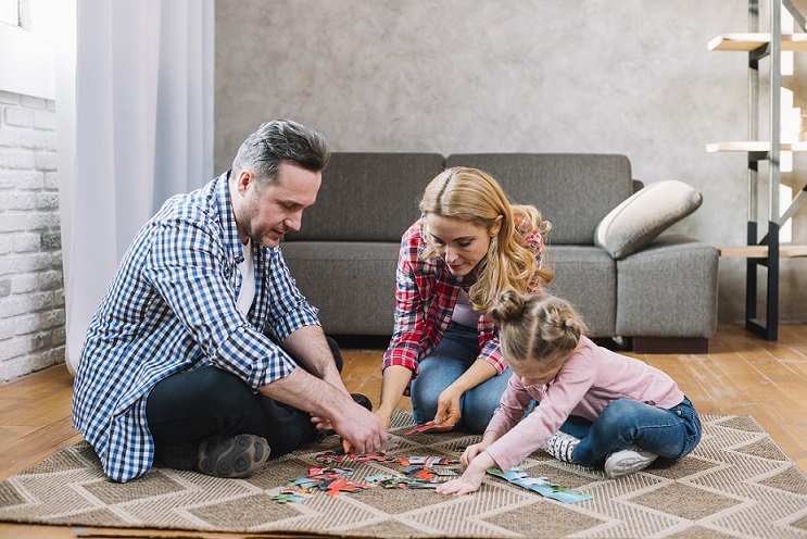 child solving jigsaw pattern with parents